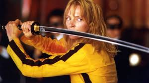 Une femme habiller en jaune avec du sang sur les bras, tiens un katana à son visage.