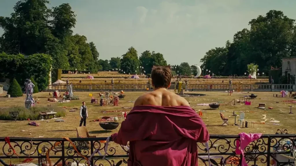 Le personnage d'Oliver est en robe de chambre rouge sur un balcon. Il regarde le désastre de la fête de la veille.
