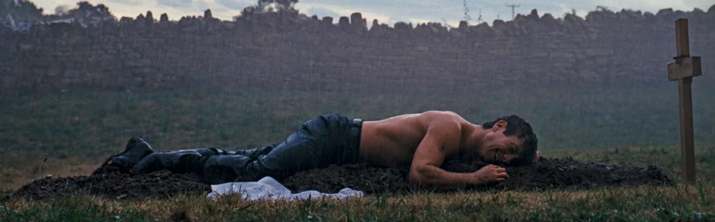 Le personnage d'Oliver est sur un tombe, sans chandail, qui pleure, sous la pluie.