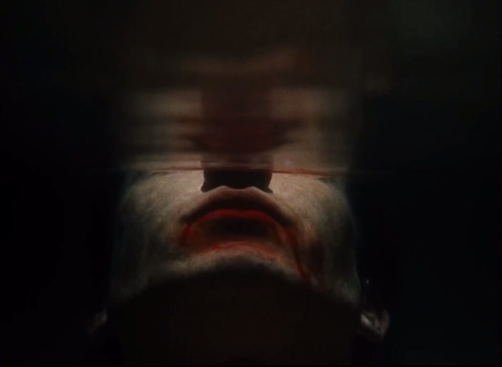 Un homme avec un bouche recouvert de sang, dans l'eau.